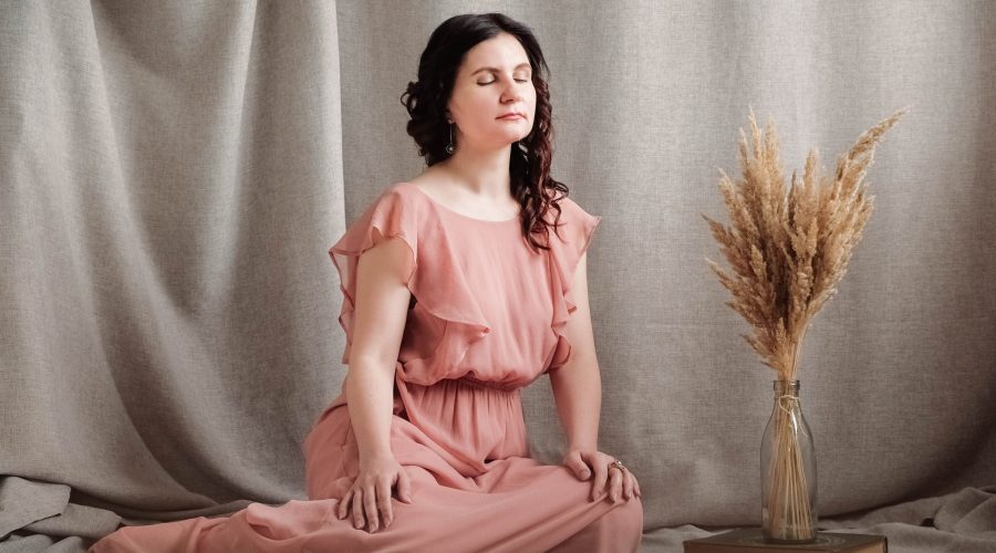 Beautiful brunette woman in a pink dress on a background of linen fabric. Copy, empty space for text.